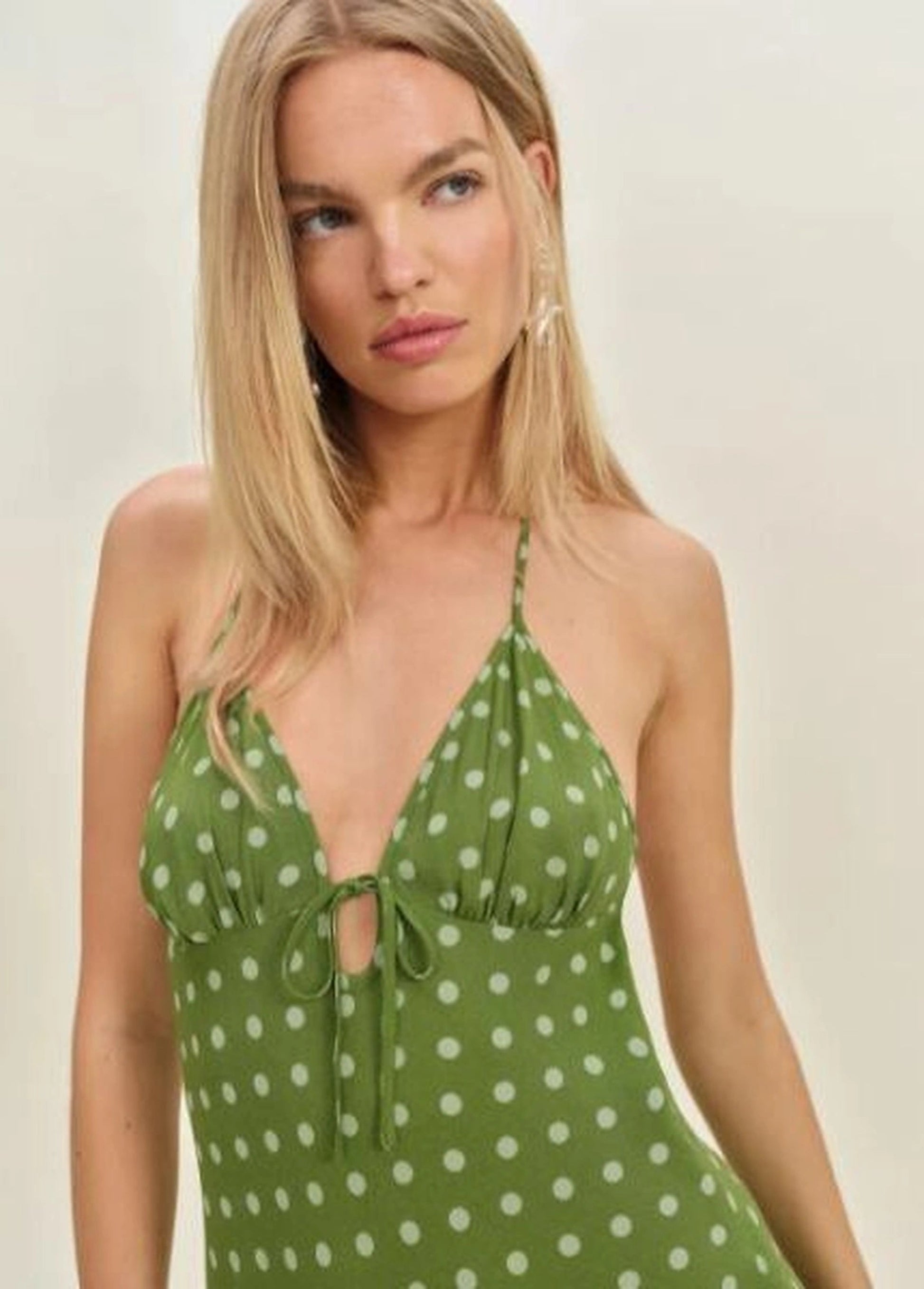 Fiora Dress in black LENZING™ ECOVERO™ viscose crepe, showcasing its halter neckline and empire silhouette on a woman in a summer setting.