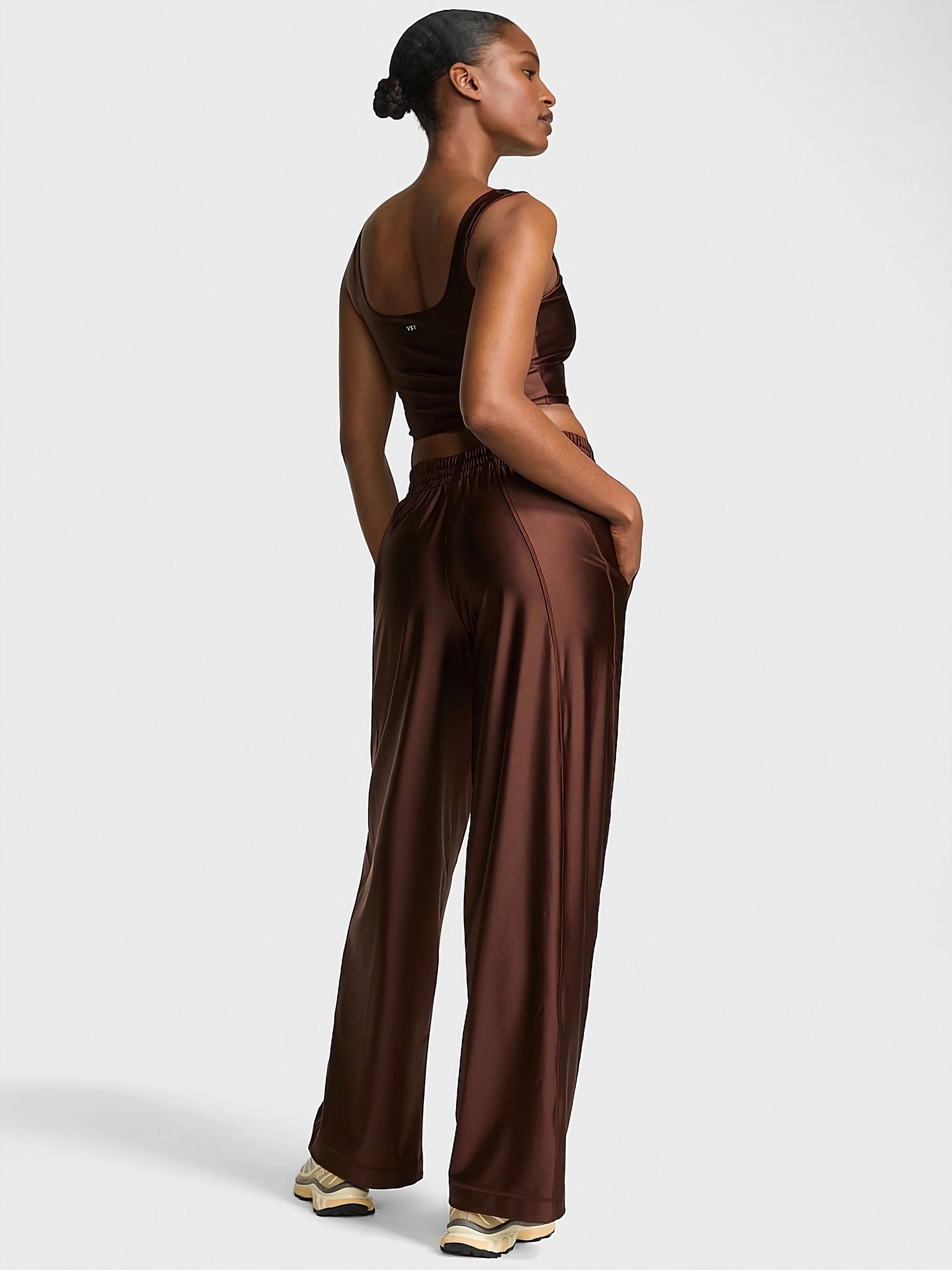 VSX GlossyTech Wide-Leg Pant in black, showcasing its high-shine finish and fluid, wide-leg silhouette on a woman in motion