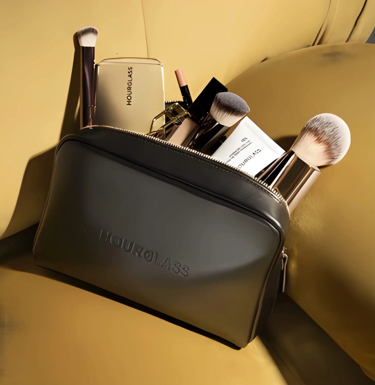 he Hourglass Essentials Set open on a marble surface, showcasing the Ambient Lighting Palette, Unlocked Mascara, and vegan leather bag for a ritual of radiant elegance.