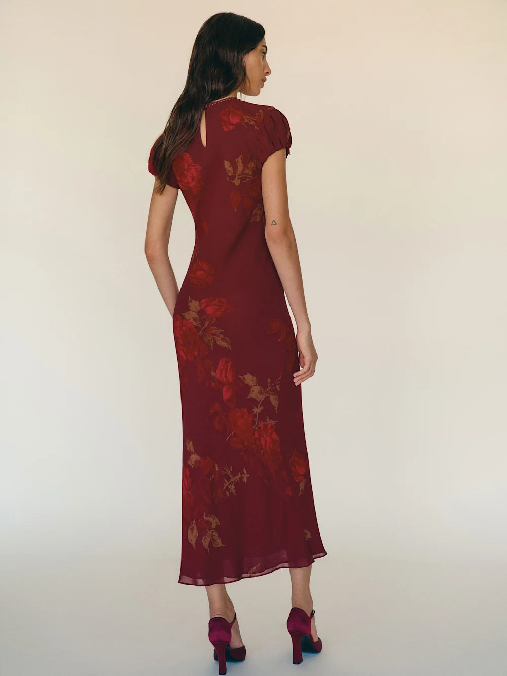 Woman wearing a burgundy floral dress against a white background