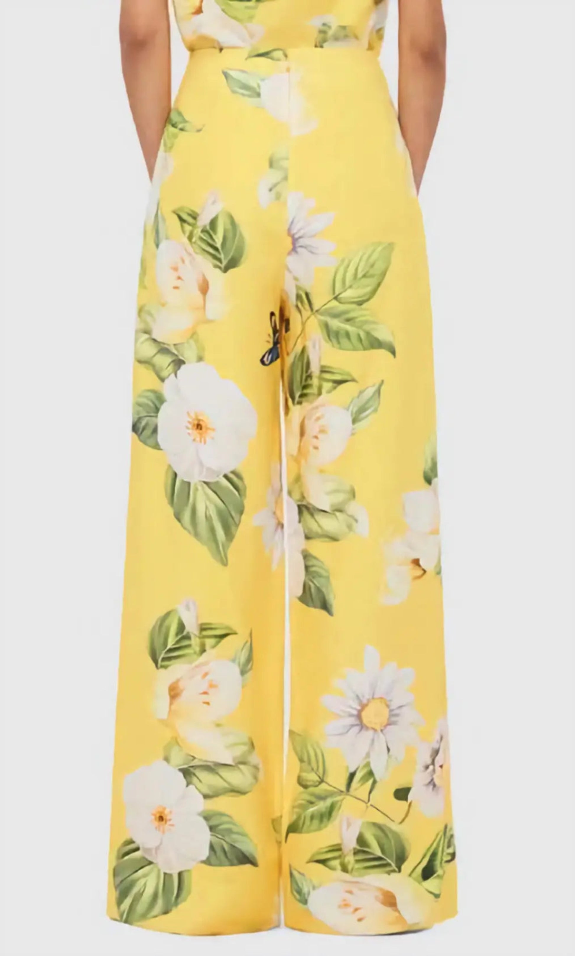 Yellow floral dress with white flowers and green leaves on a plain background