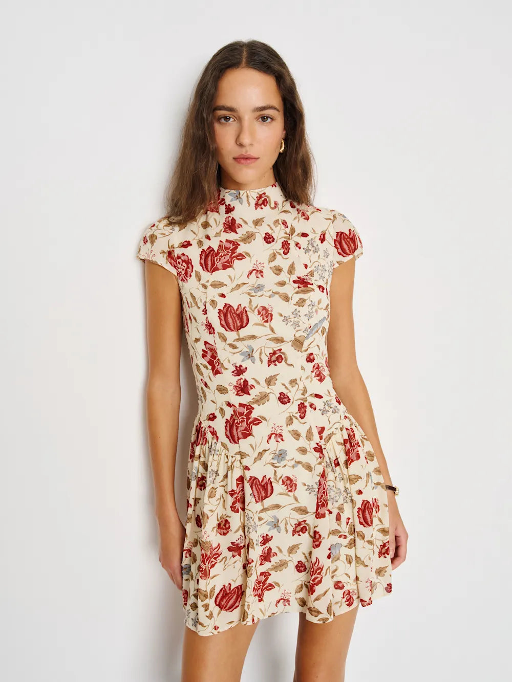Woman wearing a floral dress with red and beige pattern on a white background