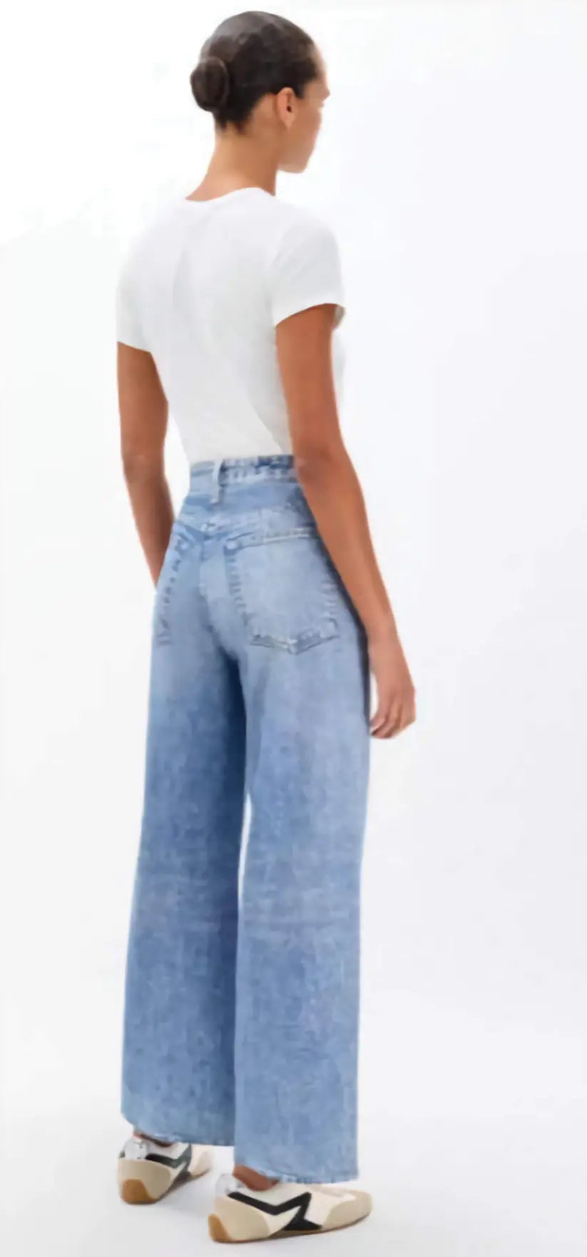 Person wearing light blue jeans and a white shirt on a white background