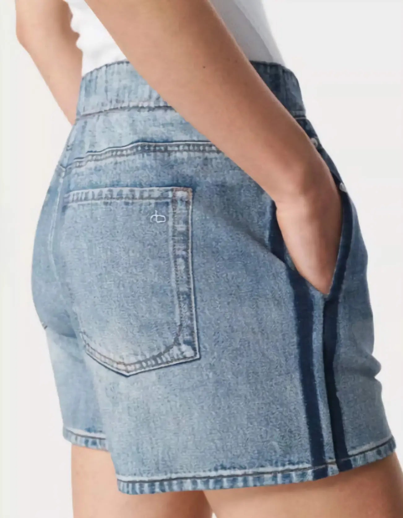 Denim shorts worn by a person on a plain background