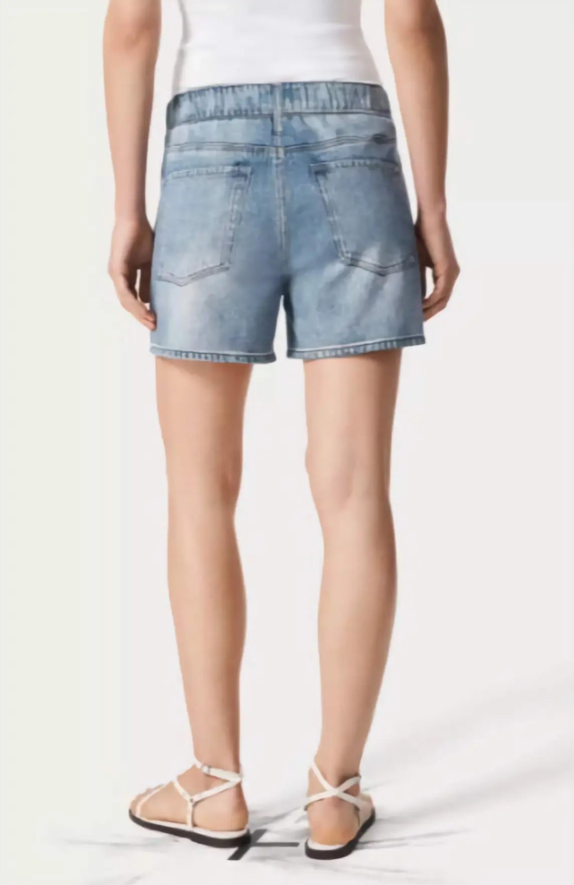 Person wearing light blue denim shorts on a white background