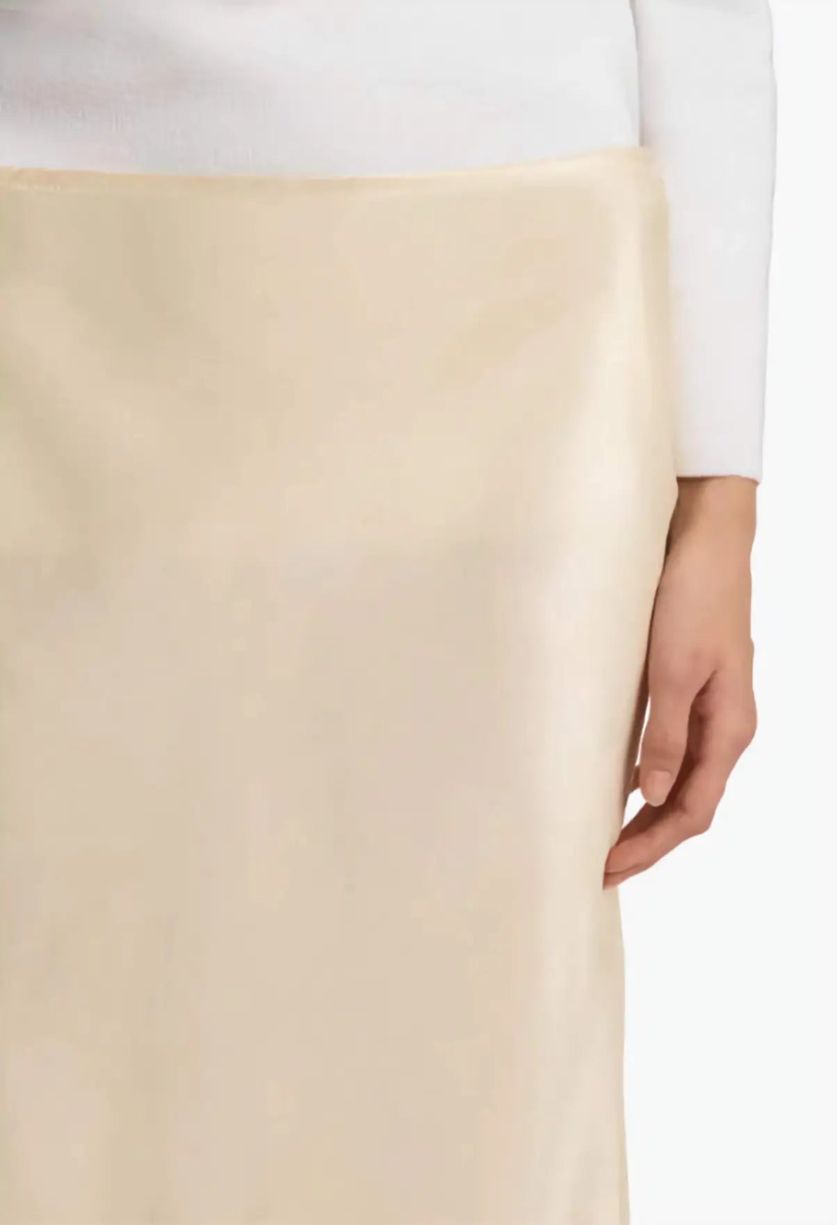 Beige skirt worn with a white top, focusing on the garment.