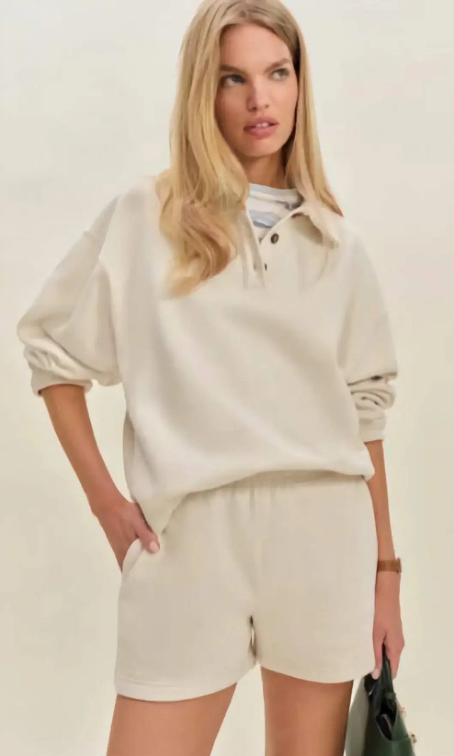 Woman in a modern setting wearing the Nico Classic Polo Sweatshirt in cream, embodying elevated comfort and strategic recalibration.