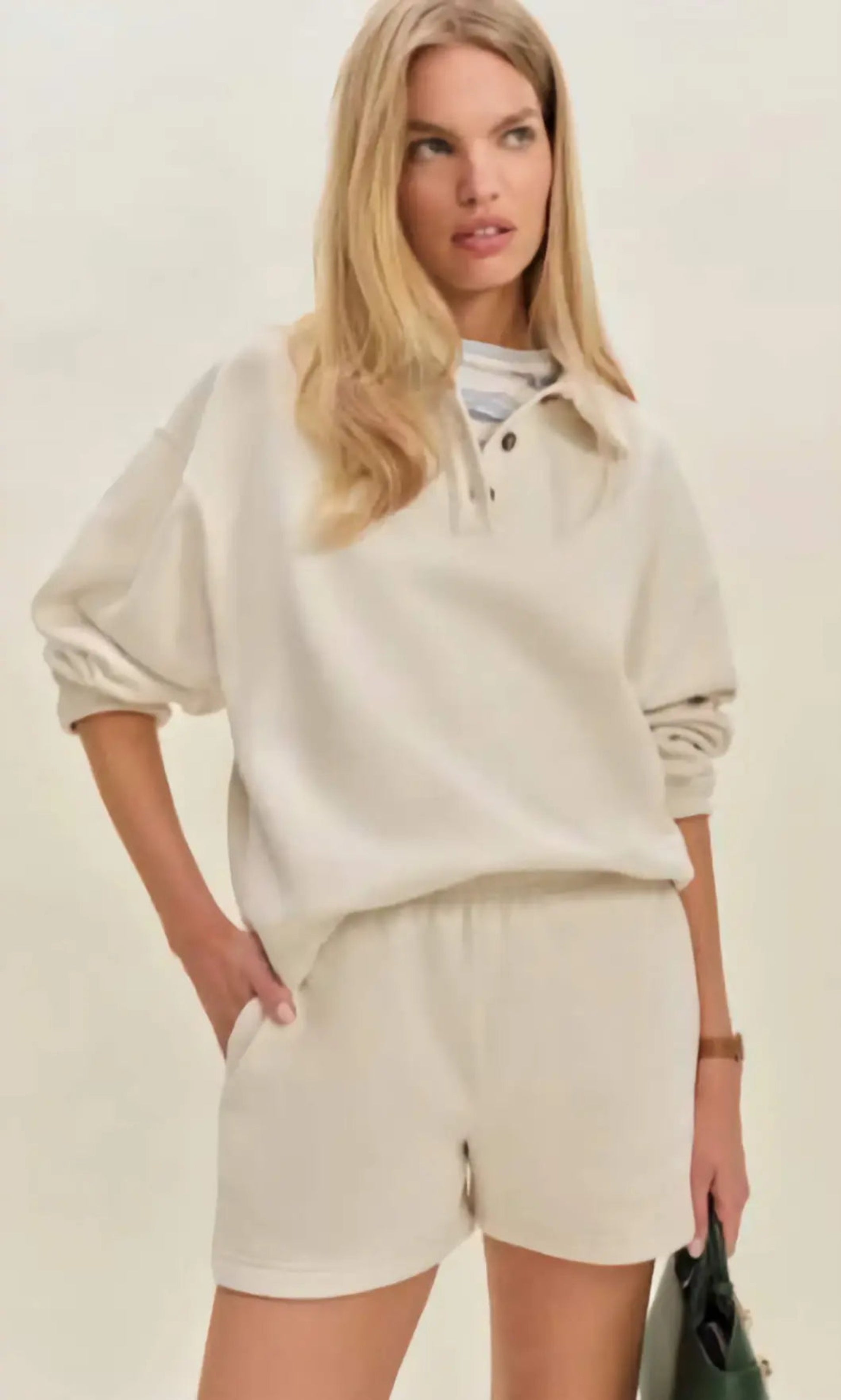 Woman in a modern setting wearing the Nico Classic Polo Sweatshirt in cream, embodying elevated comfort and strategic recalibration.