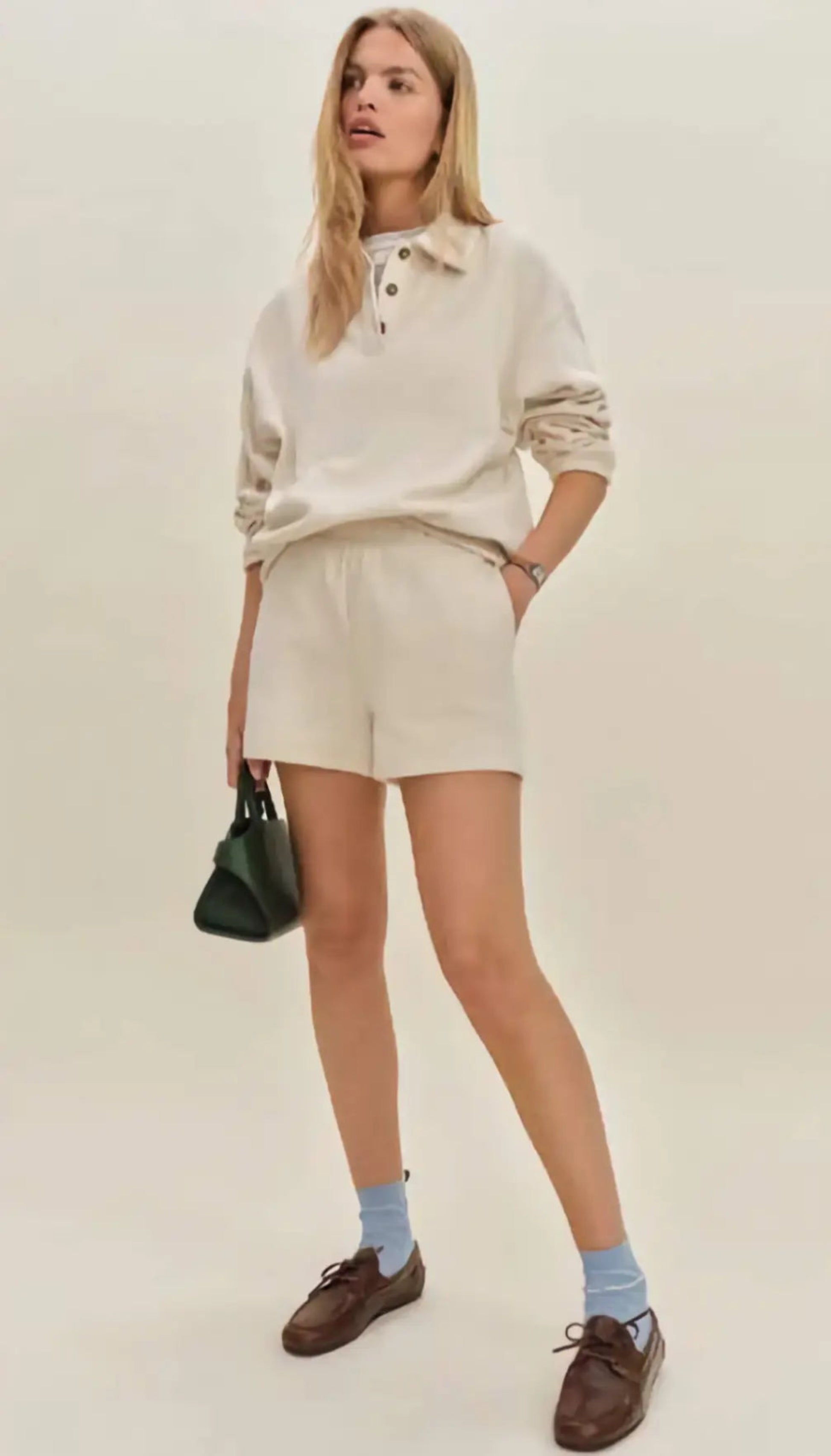 Woman in a modern setting wearing the Nico Classic Polo Sweatshirt in cream, embodying elevated comfort and strategic recalibration.