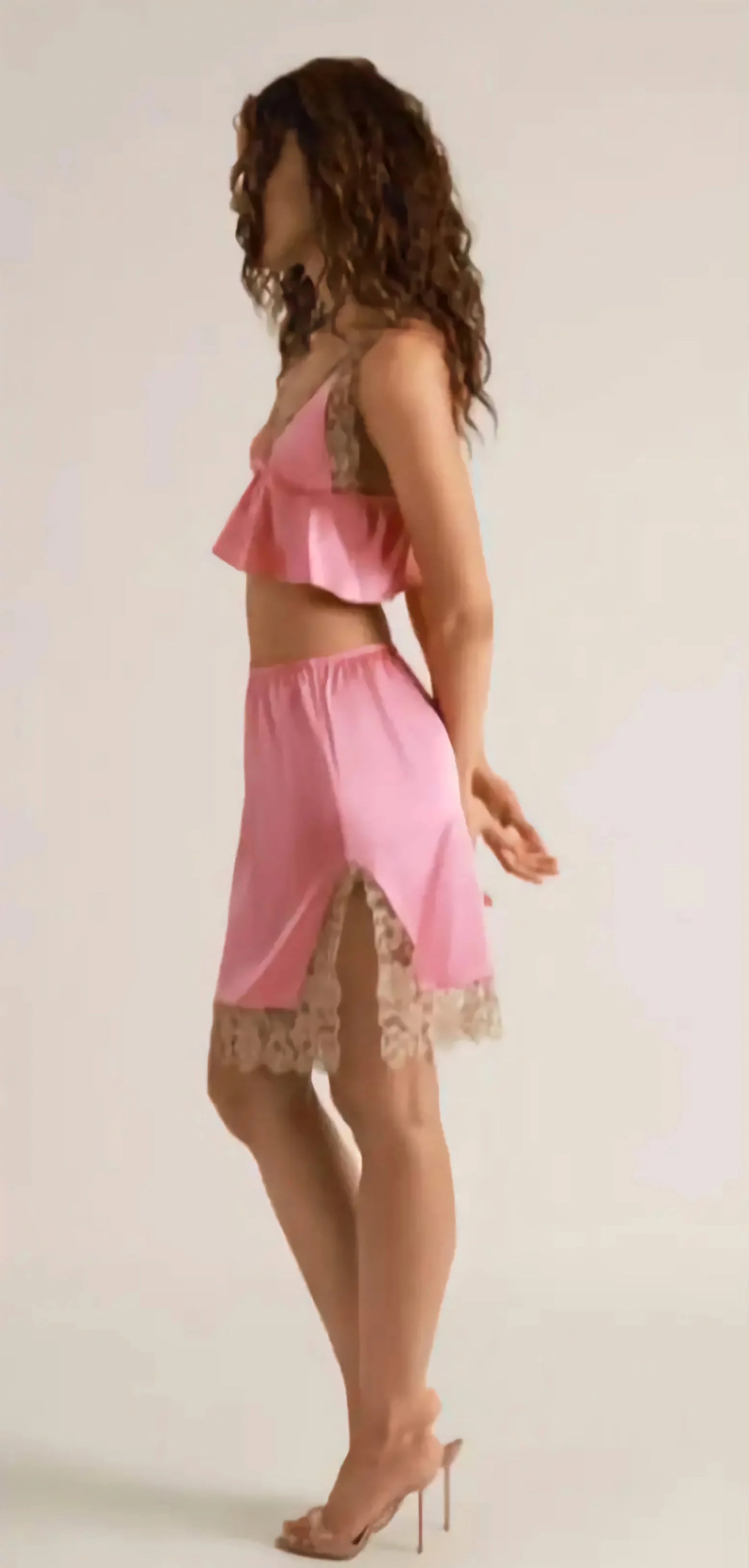 Woman wearing a pink lace outfit on a plain background