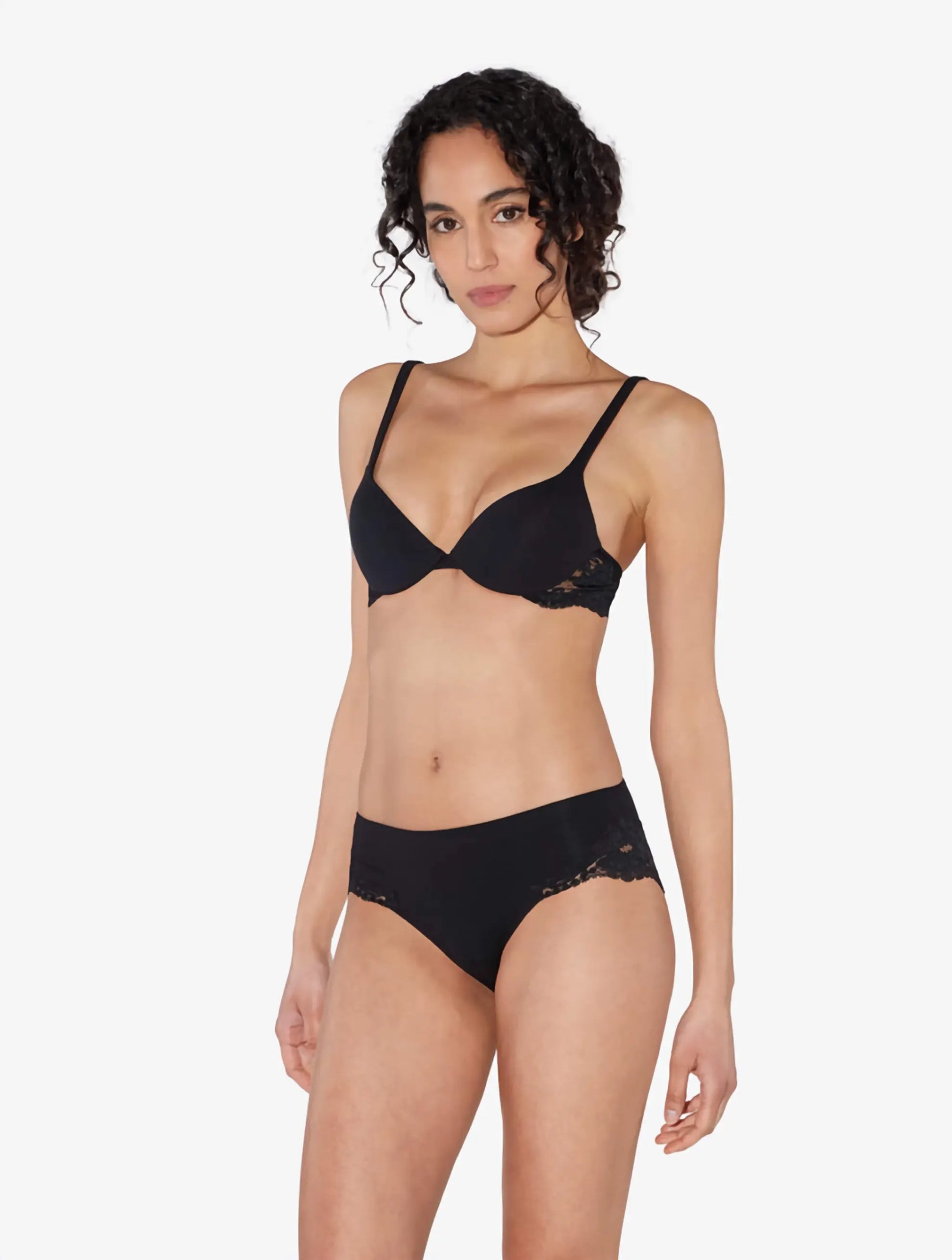 Woman wearing a black bra and panties set on a white background