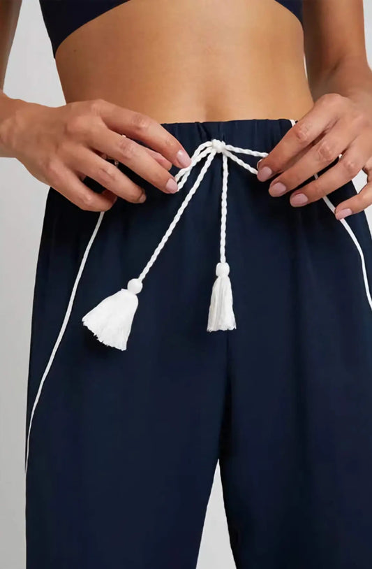 The Supreme Jogger Pant in navy with crisp white contrast piping, shown on a model in motion, highlighting the harem silhouette and tailored drape.