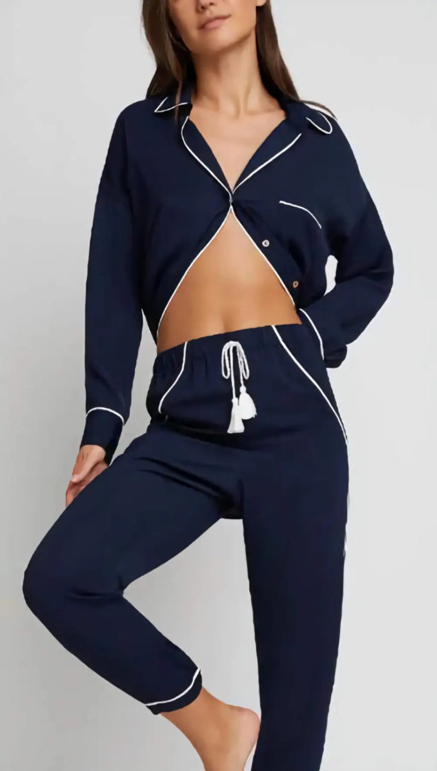 Woman wearing a navy blue tracksuit with white piping on a gray background