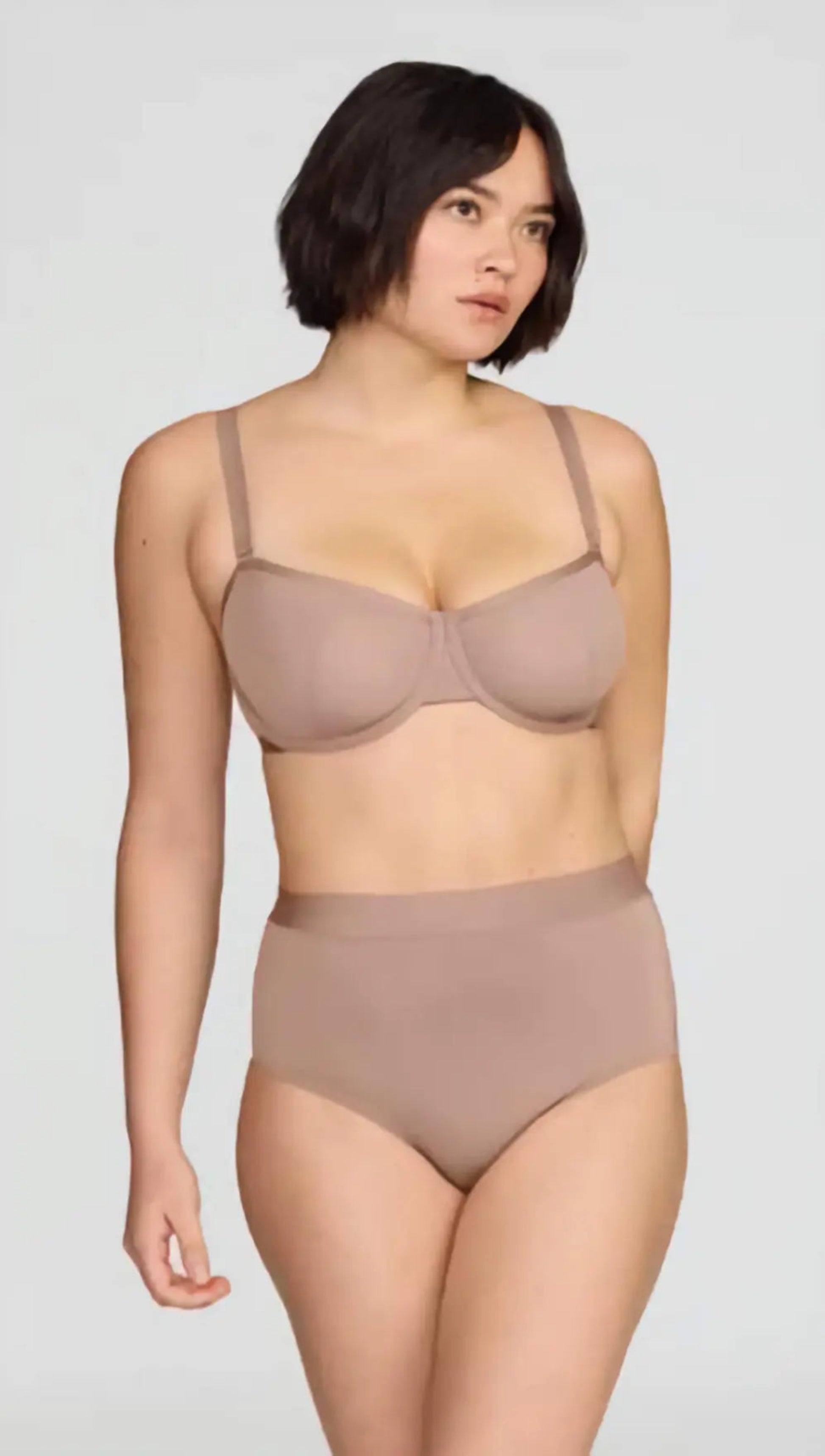 Woman wearing a beige bra and high-waisted underwear set on a white background