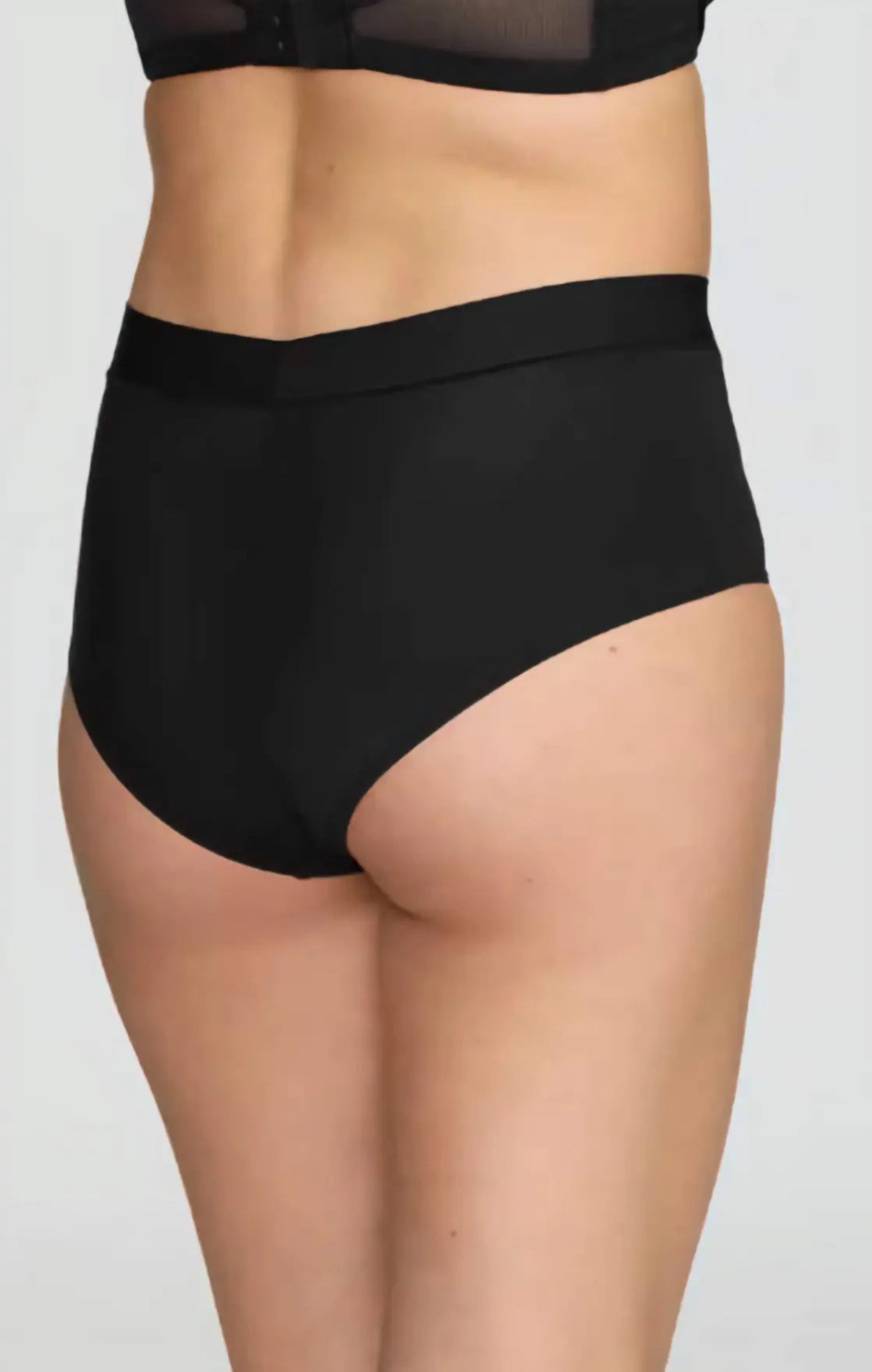Black high-waisted underwear worn by a person on a plain background
