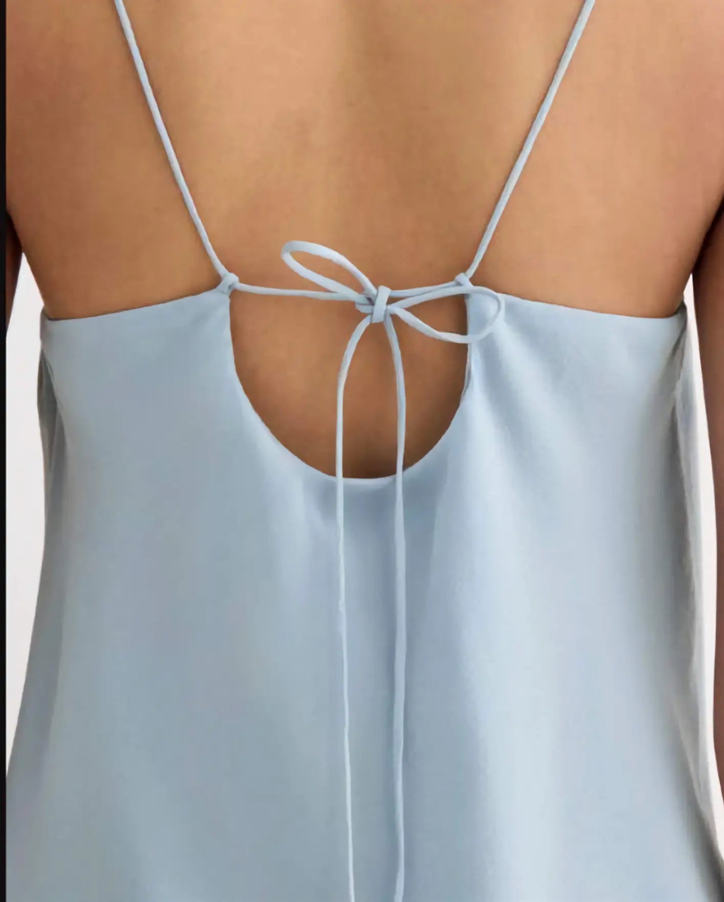 Light blue dress with thin straps and a tie detail on a neutral background