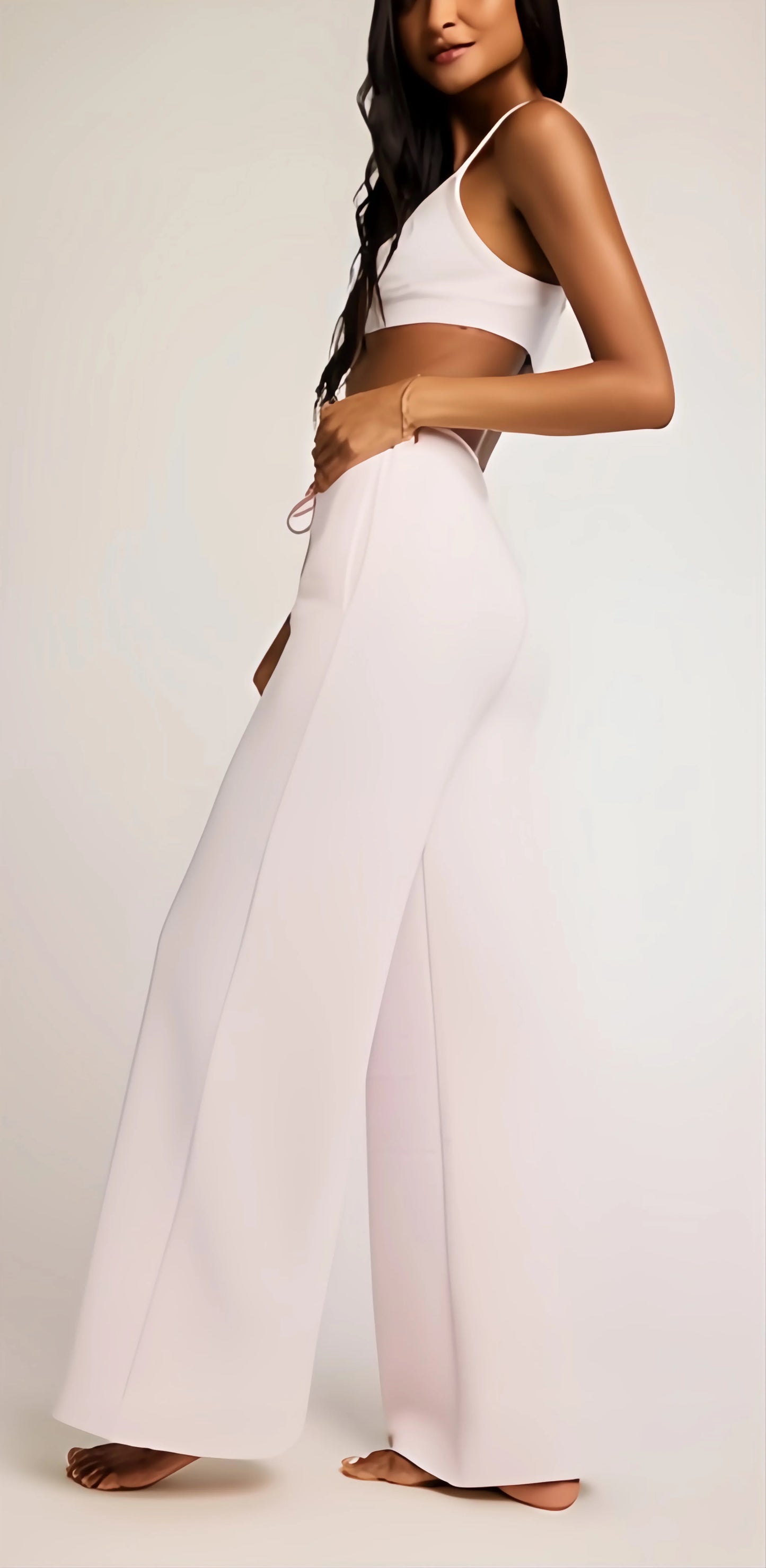 Woman in a minimalist interior wearing the Waffle Knit Track Pant in heather grey, showcasing its high-rise waist and fluid wide-leg drape during a moment of intentional rest.