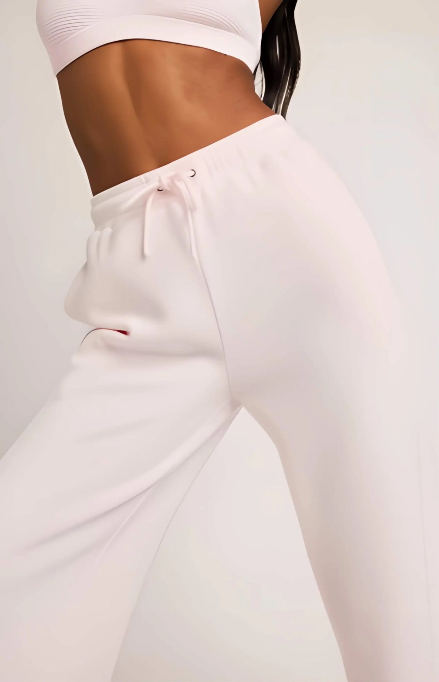 White jogger pants worn by a person on a light gray background