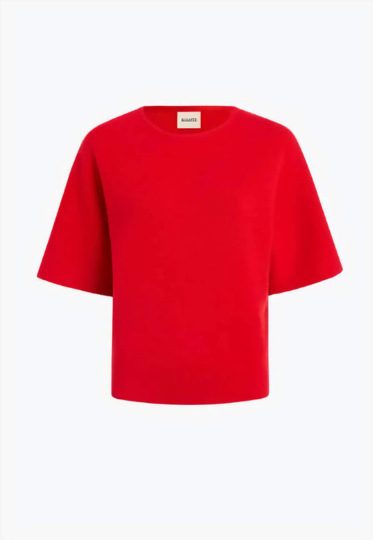 The Warren Top in fire red compact Merino wool, showcasing the Milano stitch texture and wide sleeves on a model in a minimalist setting.