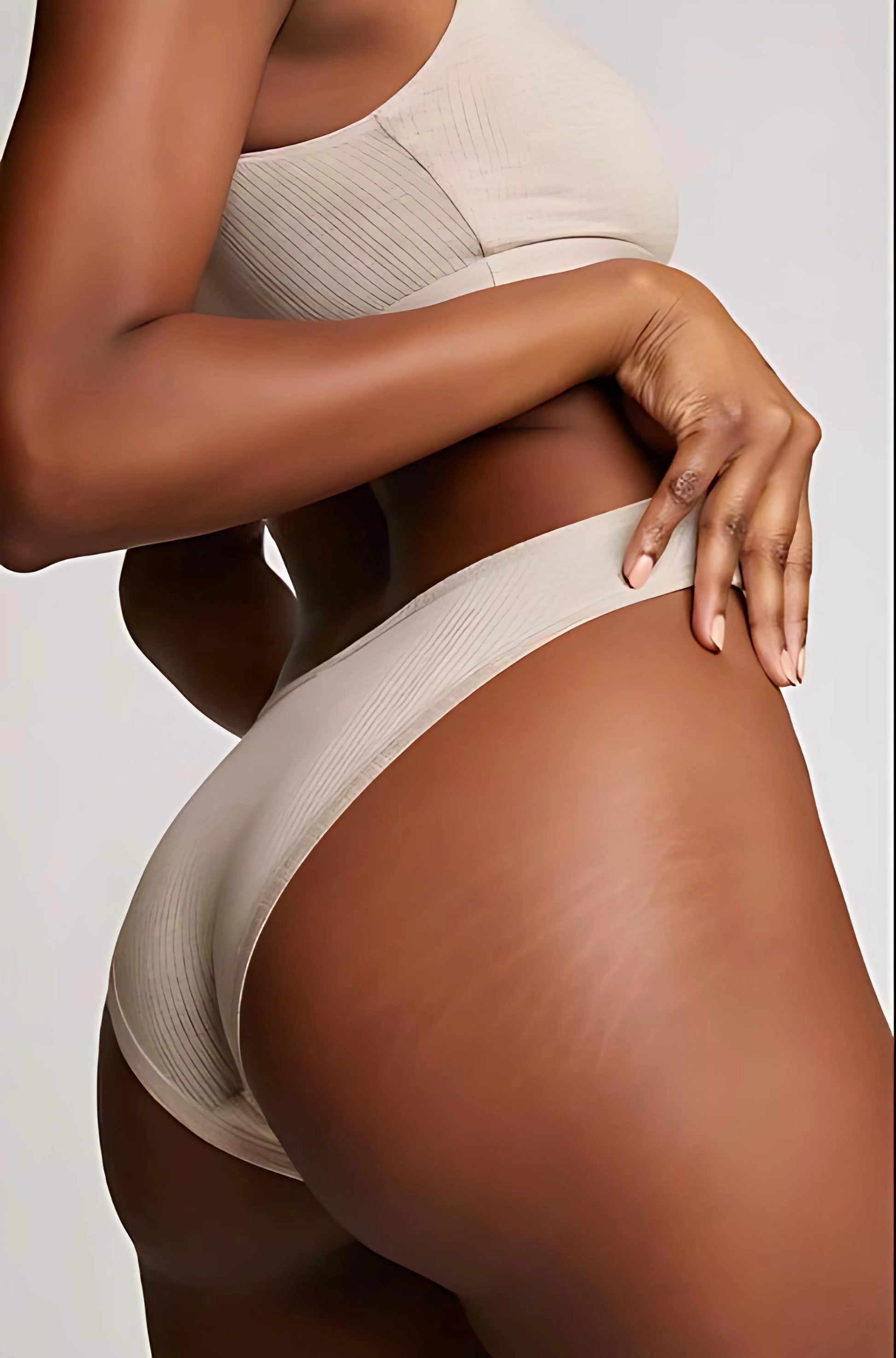 Person wearing a beige bra and underwear set on a plain background