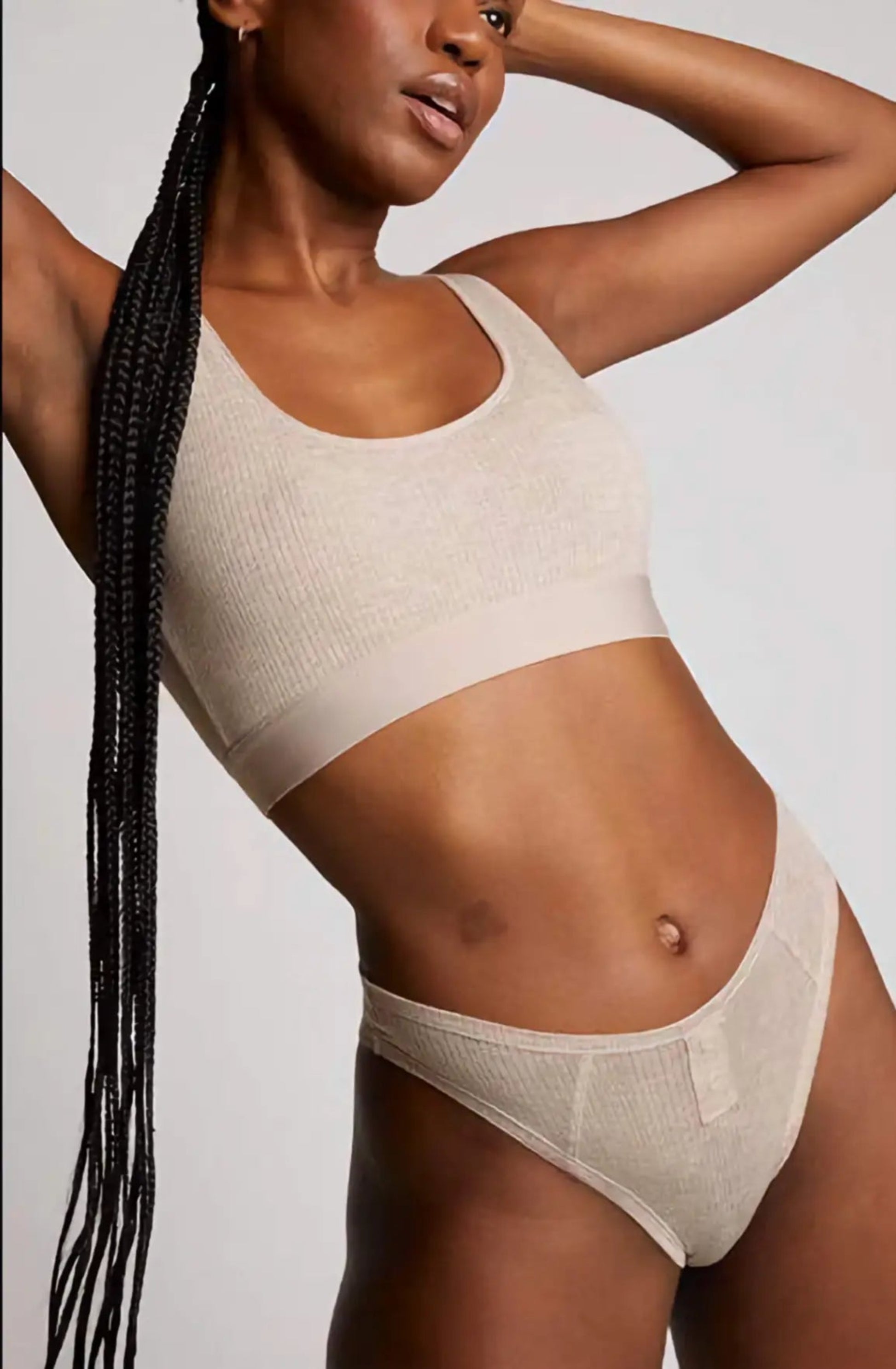 Woman wearing a beige bikini set against a plain background