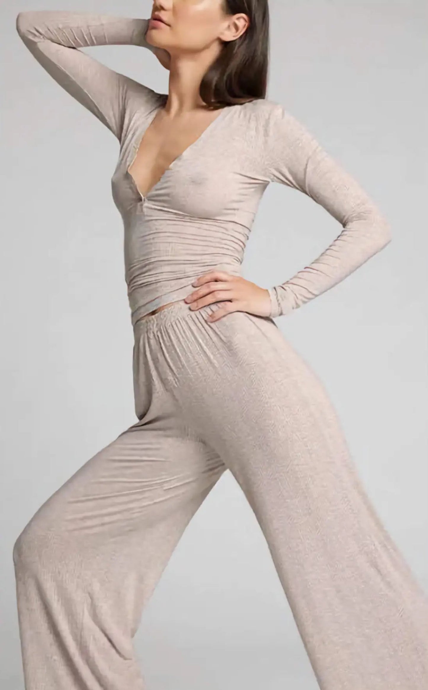 Woman wearing a beige jumpsuit against a plain background
