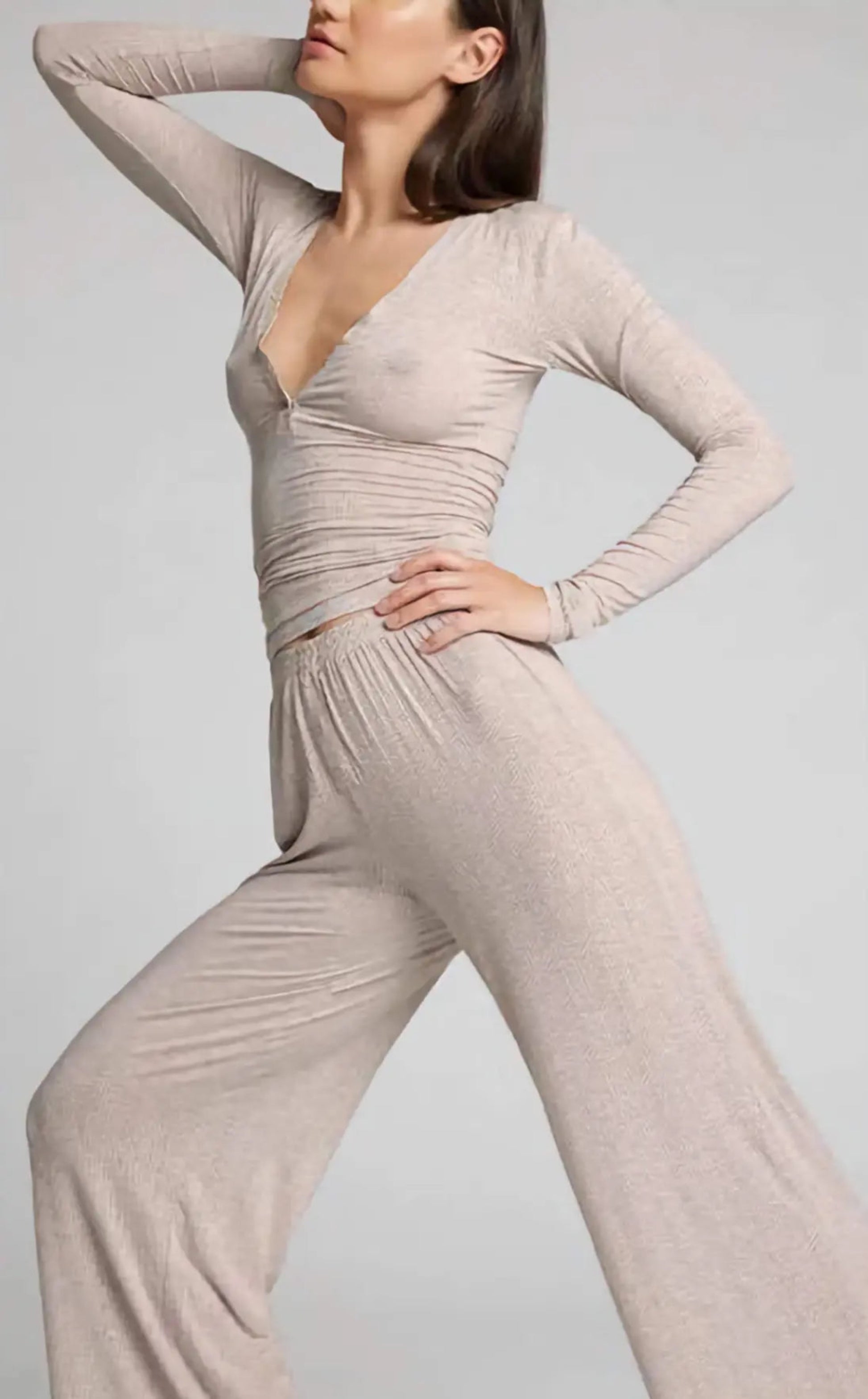 Woman wearing a beige jumpsuit against a plain background