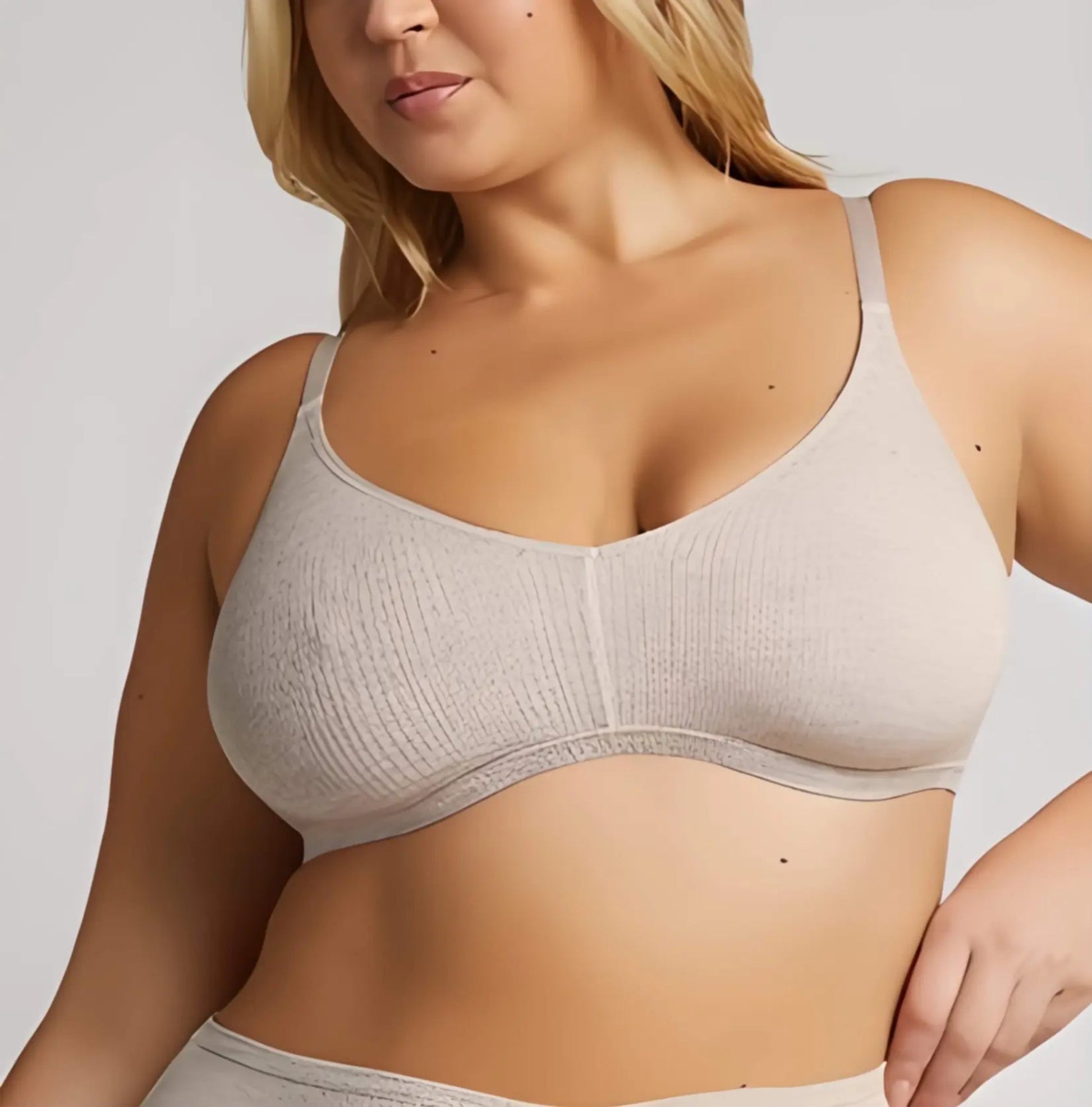 Woman wearing a beige bra against a plain background