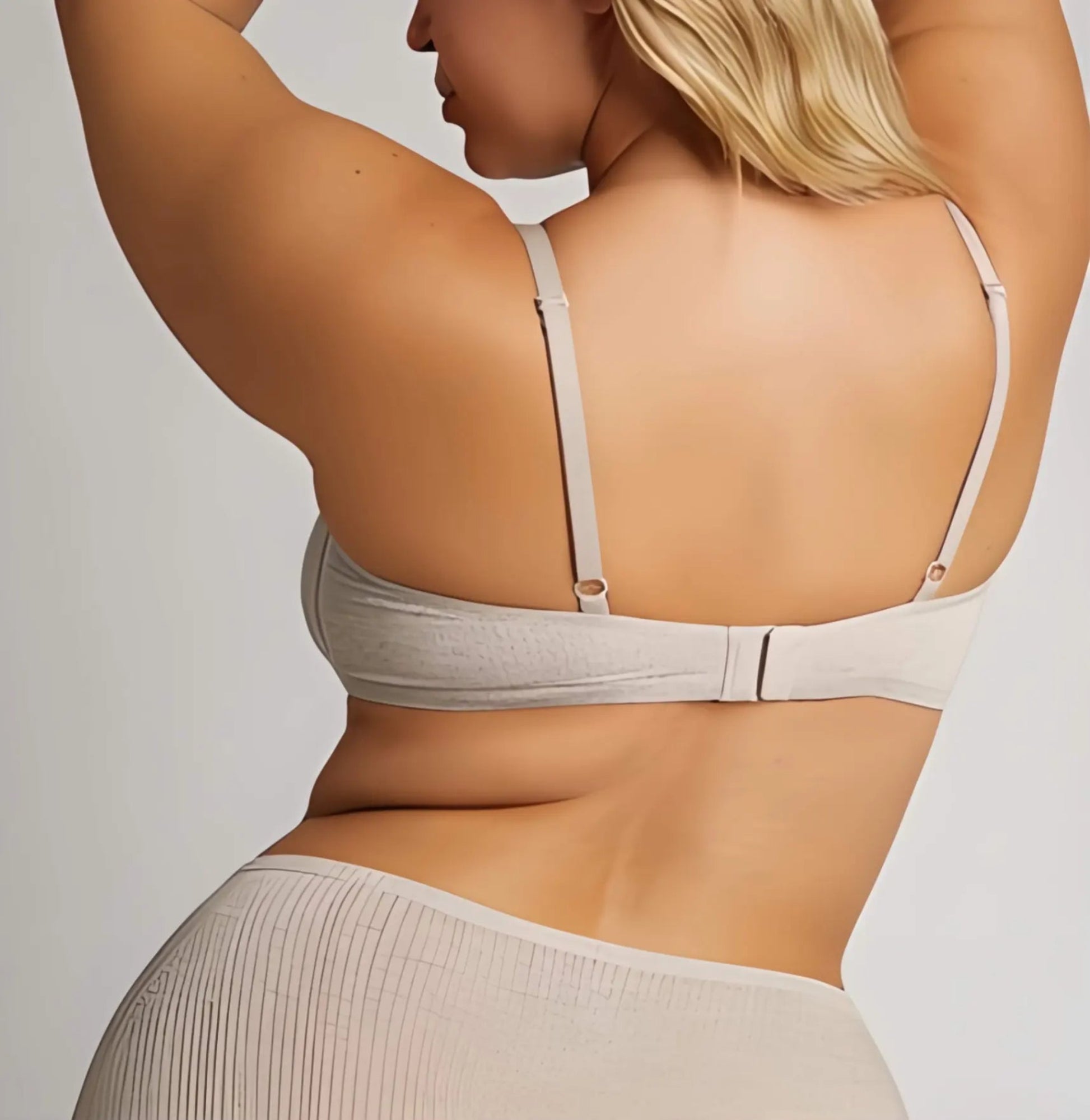 Woman wearing a beige bra and underwear set against a plain background