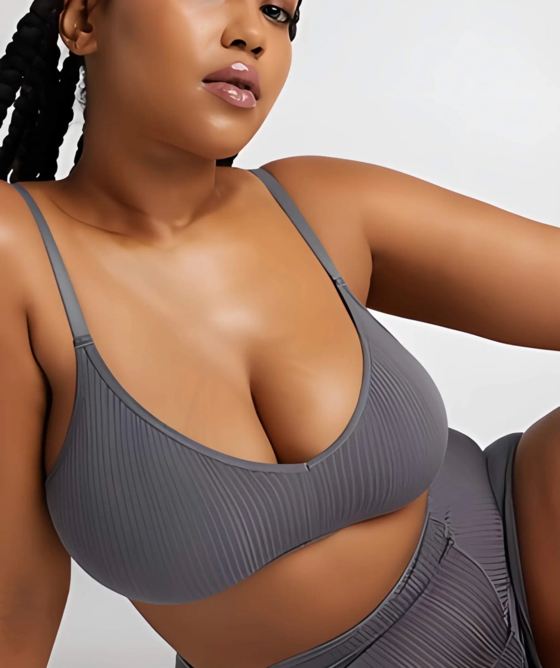 Woman wearing a gray sports bra and leggings on a white background