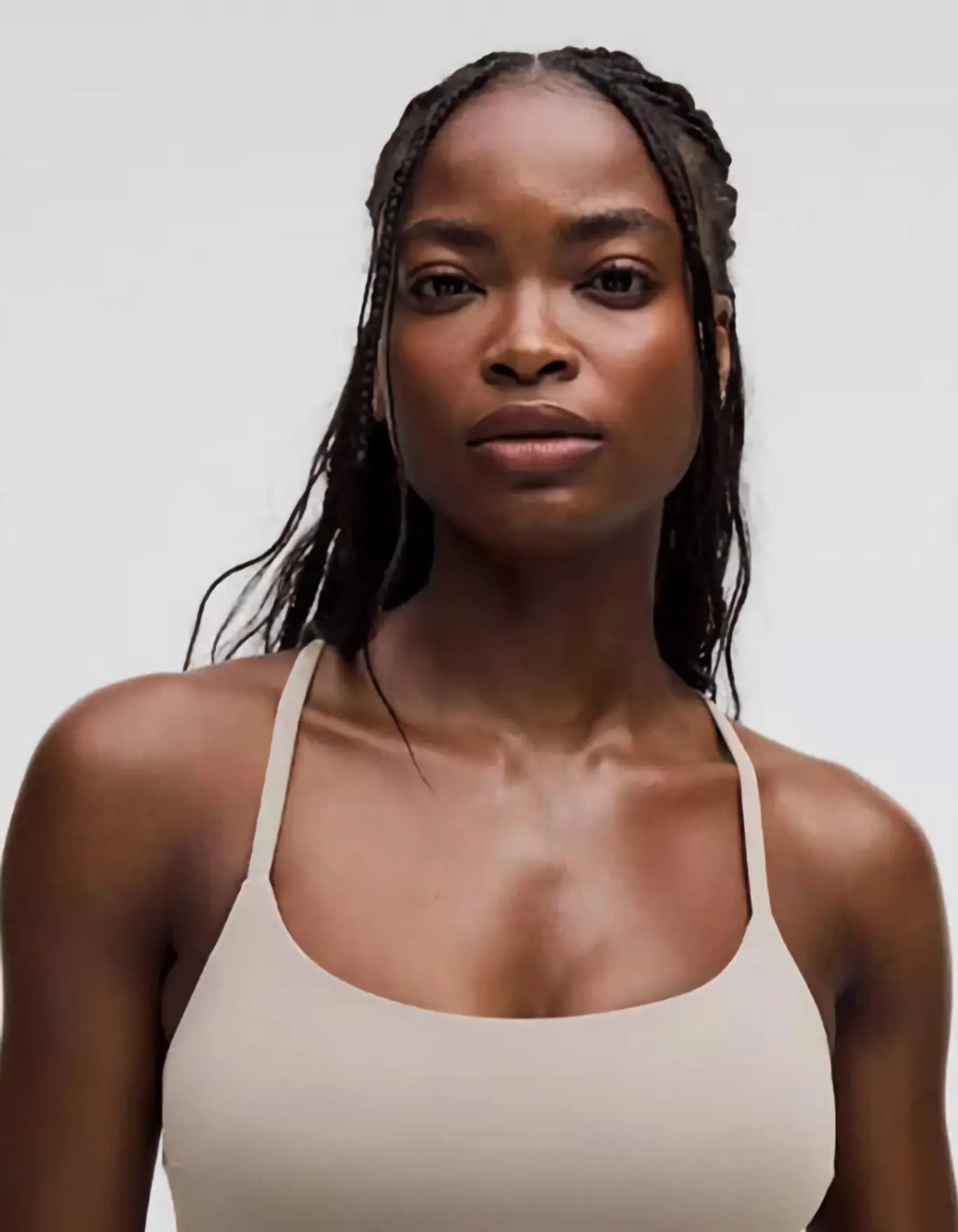 Woman wearing a beige tank top against a plain background