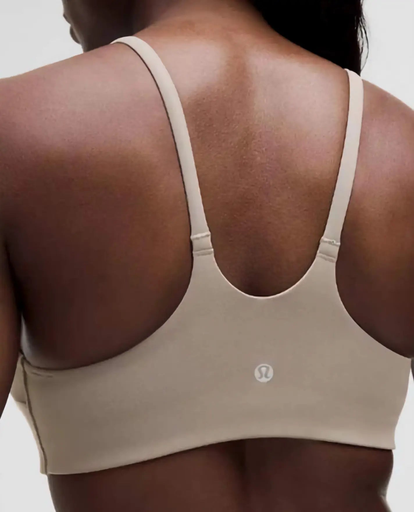 Beige sports bra with brand logo on a neutral background